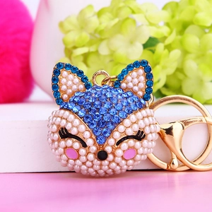 Sparkling fox head keychain with blue crystals and white pearls on golden metal ring