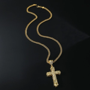 Close-up of a golden cross pendant with sparkling rhinestones on a black background