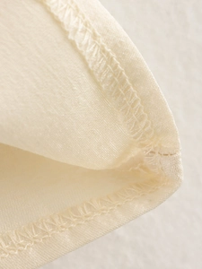 Detailansicht der Overlock-Naht und halbtransparenten Stofftextur bei der beigen Bluse