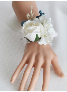 Detailed view of white rose wrist corsage with lace band and blue berry accents