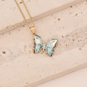 Détail d'un collier papillon doré orné de pierres bleu clair et de zircons blancs