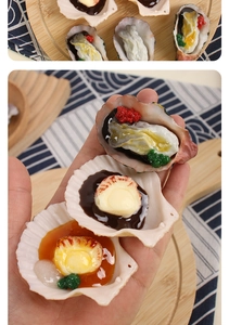 Macro detail of realistic roasted oyster and scallop food model keychain held in hand
