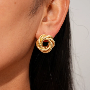 Detailed side view of a gold-plated twisted spiral stud earring worn by a model