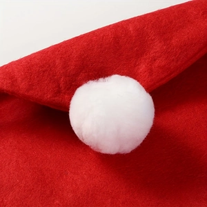Close-up of red plush fabric texture and white pom-pom detail on Christmas chair cover