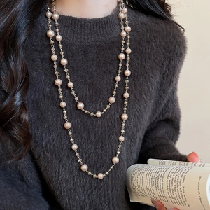 Close-up of layered French glass beads and pearls necklace on a grey sweater