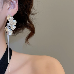 Gros plan sur les boucles d'oreilles pétales en métal argenté avec de longs pompons