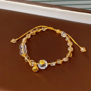 Detail of yellow citrine bead bracelet with golden lotus charm on dark leather tray