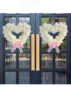 Détail d'une couronne de roses blanches en forme de cœur avec un ruban rose élégant