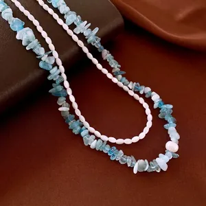 Doppellagiges Aquamarin- und Perlenarmband mit blauen Steinen auf Seidenhintergrund