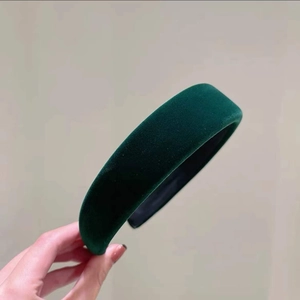 Détail d'un serre-tête en velours vert foncé montrant la texture et le style vintage