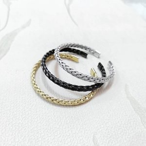 Three braided stainless steel open bangles in gold, silver, and black finish