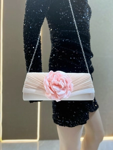 Pink pleated clutch bag featuring a large fabric flower and elegant chain strap detail.