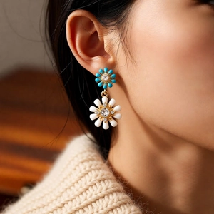 Gros plan sur des boucles d'oreilles à fleurs doubles avec émail bleu et blanc et cristaux