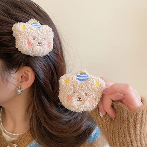 Close-up of cute beige flocked bear hair pins with blue striped hats worn on hair