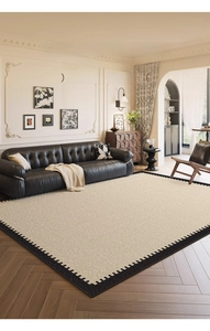 Detail of cream beige area rug with black sawtooth geometric edge on wood flooring