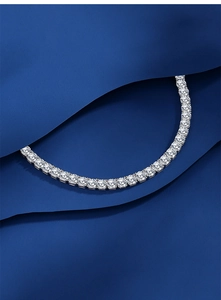 Macro shot of silver tennis bracelet with brilliant cut cubic zirconia on blue silk
