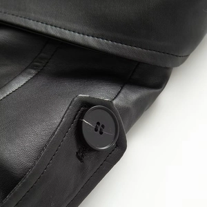 Close-up of black faux leather coat featuring metallic buttons and detailed stitching