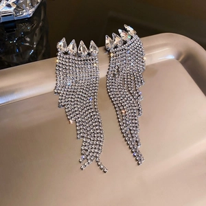 Détail de boucles d'oreilles élégantes avec feuilles émeraude et franges argentées scintillantes