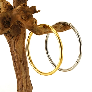 Minimalist 18K gold and silver plated titanium steel bangles on a natural wooden stand