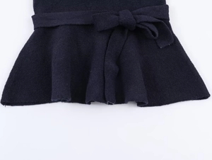 Close-up of knit top hem with bow tie detail and ruffled edge in dark navy blue