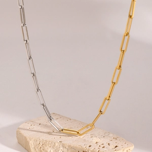 Macro view of dual-tone silver and gold paperclip link necklace on a stone base