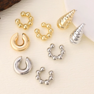 Detail of gold and silver textured C-shaped ear cuffs and bead earrings set