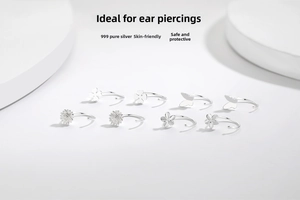 Macro detail of 999 sterling silver stud earrings featuring clover and butterfly motifs