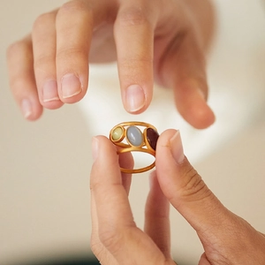 Adjustable gold ring with three colorful oval gemstones in red blue and yellow