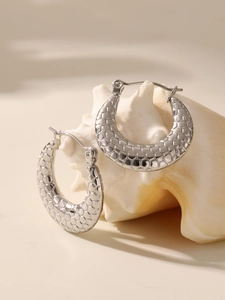 Detailed macro shot of silver hoop earrings featuring a precise 3D honeycomb texture