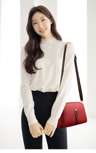Model wearing a small red leather shell crossbody bag with a dark brown shoulder strap