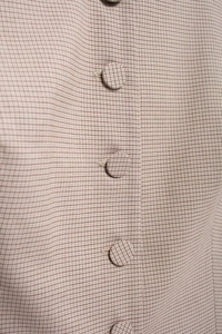 Macro shot of fabric-covered buttons on beige and brown plaid waistcoat top detail
