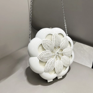 Detail of white flower evening bag featuring sparkling rhinestones and silver chain strap