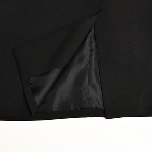 Dettaglio dell'orlo del blazer nero con spacco preciso e trama del tessuto di alta qualità