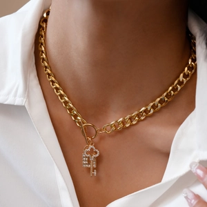 Close-up of gold chunky chain necklace with OT buckle and rhinestone key and lock charms