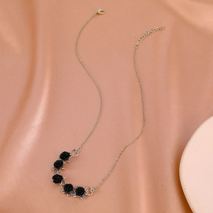 Gothic necklace detail with black 3D roses and silver heart charms on pink satin