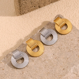 Detail shot of minimalist gold and silver hoop earrings on a textured stone surface