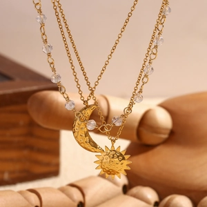 Detail of triple-layer gold necklace with sun and moon pendants and clear beads