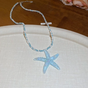 Detailed view of light blue beaded necklace with a translucent starfish pendant