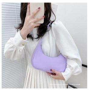 Minimalist purple crescent nylon shoulder bag shown as a sleek underarm accessory