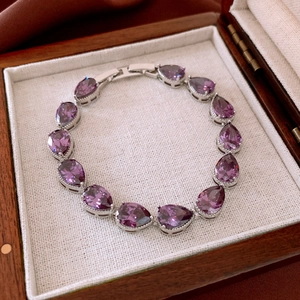 Detailed view of silver bracelet with purple pear-cut zircons in a vintage wooden box