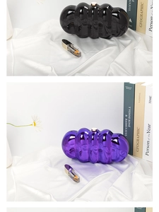 Detail of wavy ripple acrylic clutch bag in glossy black and purple on white silk fabric
