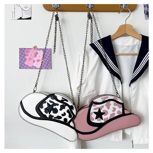 Close-up of cowboy hat shaped crossbody bags with star details hanging on wooden hooks