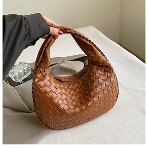 Detailed view of brown hand-woven leather texture and sturdy hobo bag handle design
