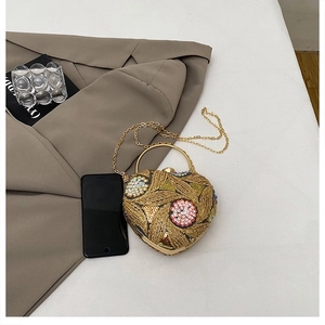 Detail of heart-shaped sequin clutch bag with floral beadwork and gold ring handle