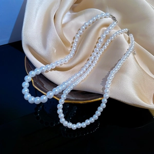 Detailed view of double-layer white pearl necklace on champagne silk satin background