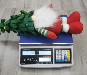 Macro view of Christmas tree gnome plush showing 316.8g weight on digital scale