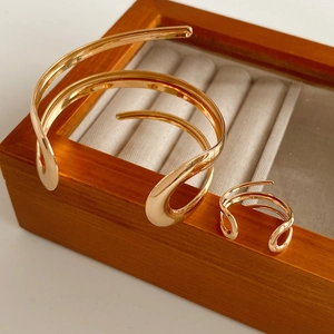 Dettaglio del set bracciale largo e anello placcati in oro in una scatola per gioielli
