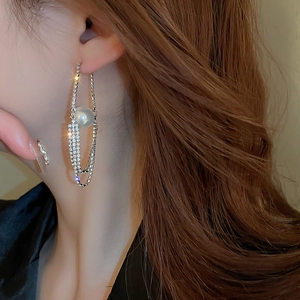 Detailed close-up of a long tassel pearl earring with sparkling rhinestones on a female model