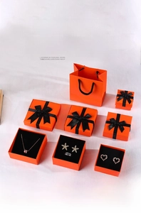 Macro shot of premium orange jewelry boxes with black ribbons and flocking foam inserts
