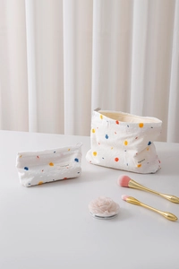 Close-up of two-piece white canvas toiletry bag set with vibrant colorful polka dots